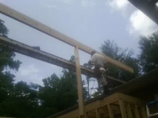 Carpenter setting a ridge beam over a new addition frame — Ice Dam Removal by Roofing Brothers in Grosse Ile