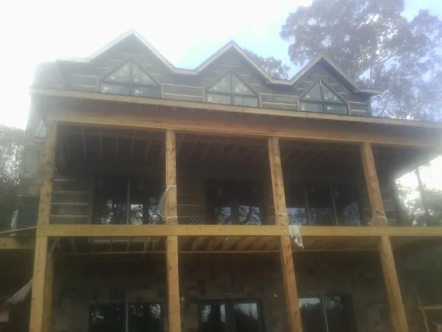 Dormers and porch framing on a large log home under construction — Roof Coating work by our crew in Grosse Ile