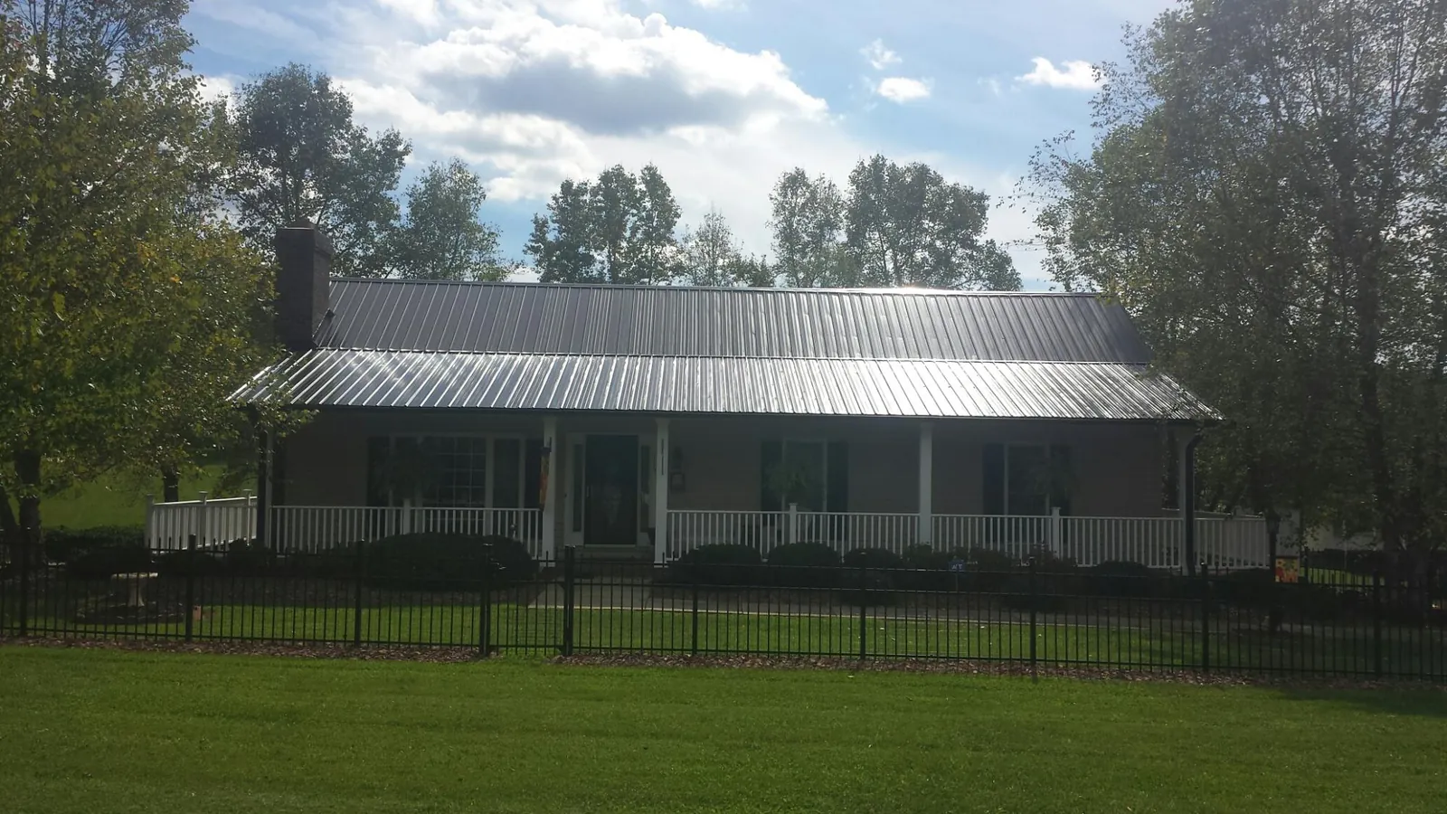 Gray metal roof on a brick ranch with a full width front porch — Gutter Guard Installation work by our crew in Grosse Ile