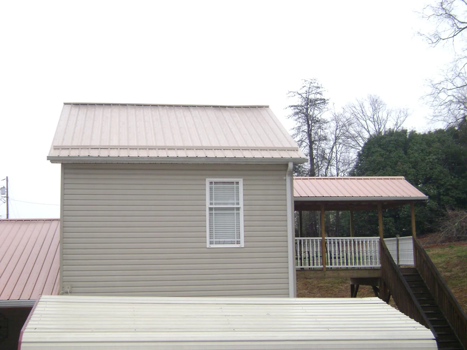 Tan metal roofs on a two story addition and attached porch, from a Roof Replacement job in Grosse Ile