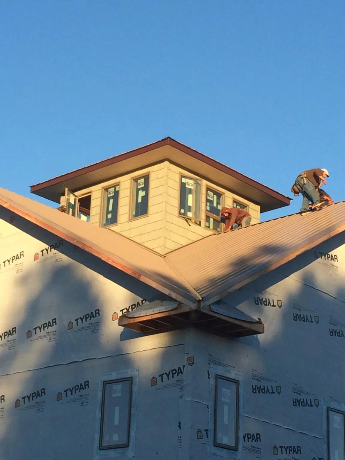 Roofers working around a rooftop cupola on a new metal roof at sunset — Roof Waterproofing in Grosse Ile by Roofing Brothers